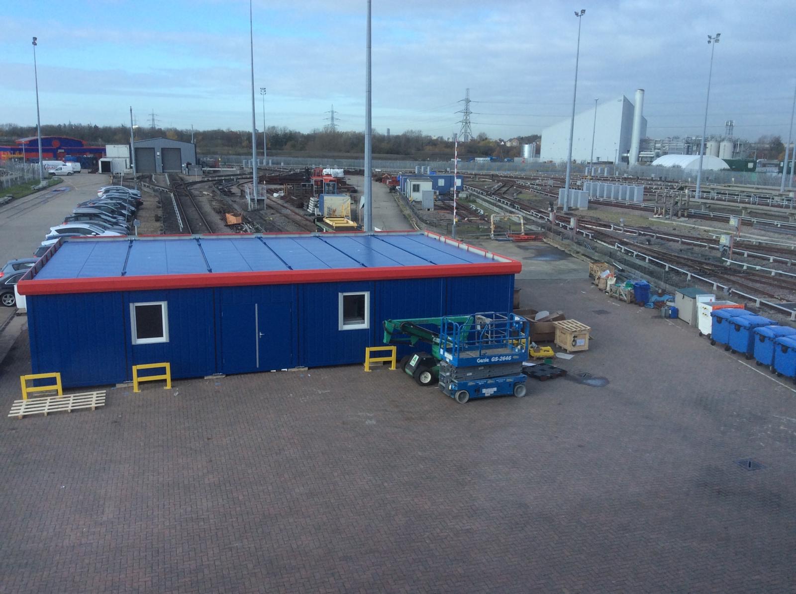 Blue and red modular office building installed at an operational rail depot