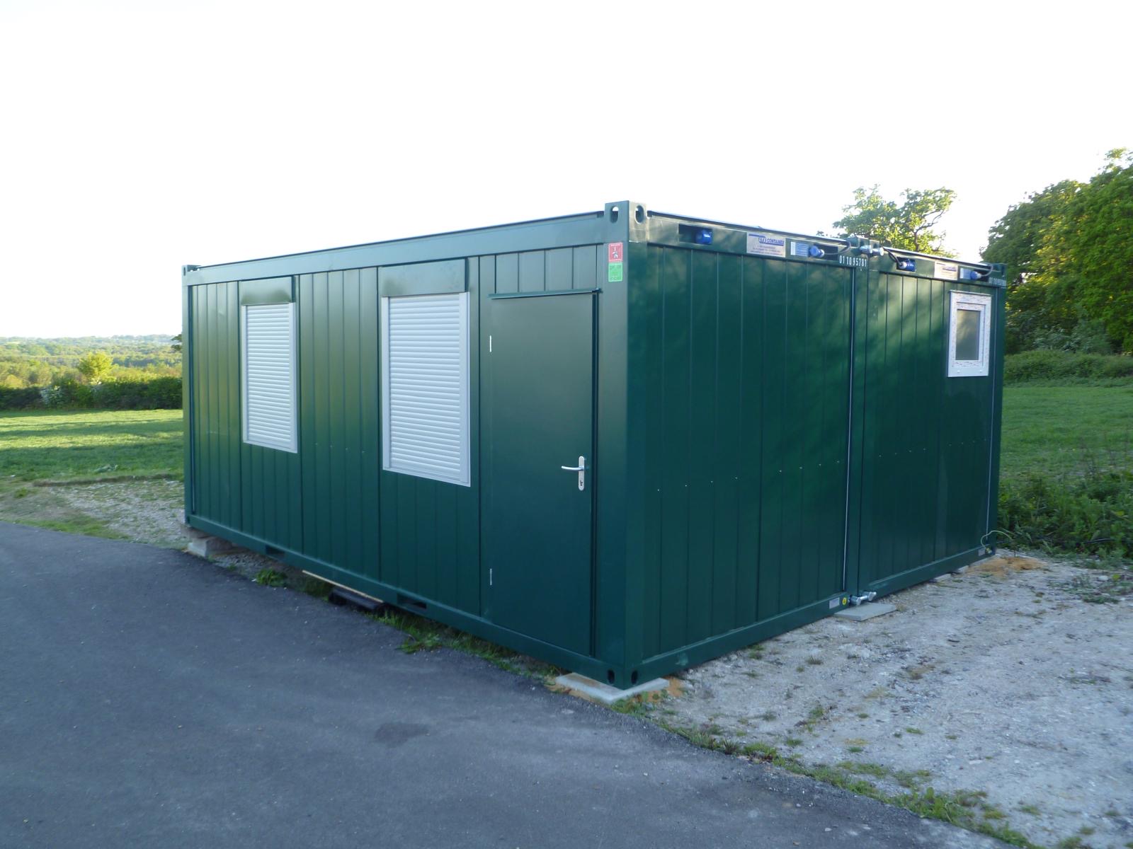Two linked green modular office cabins with picture windows on foundation pads