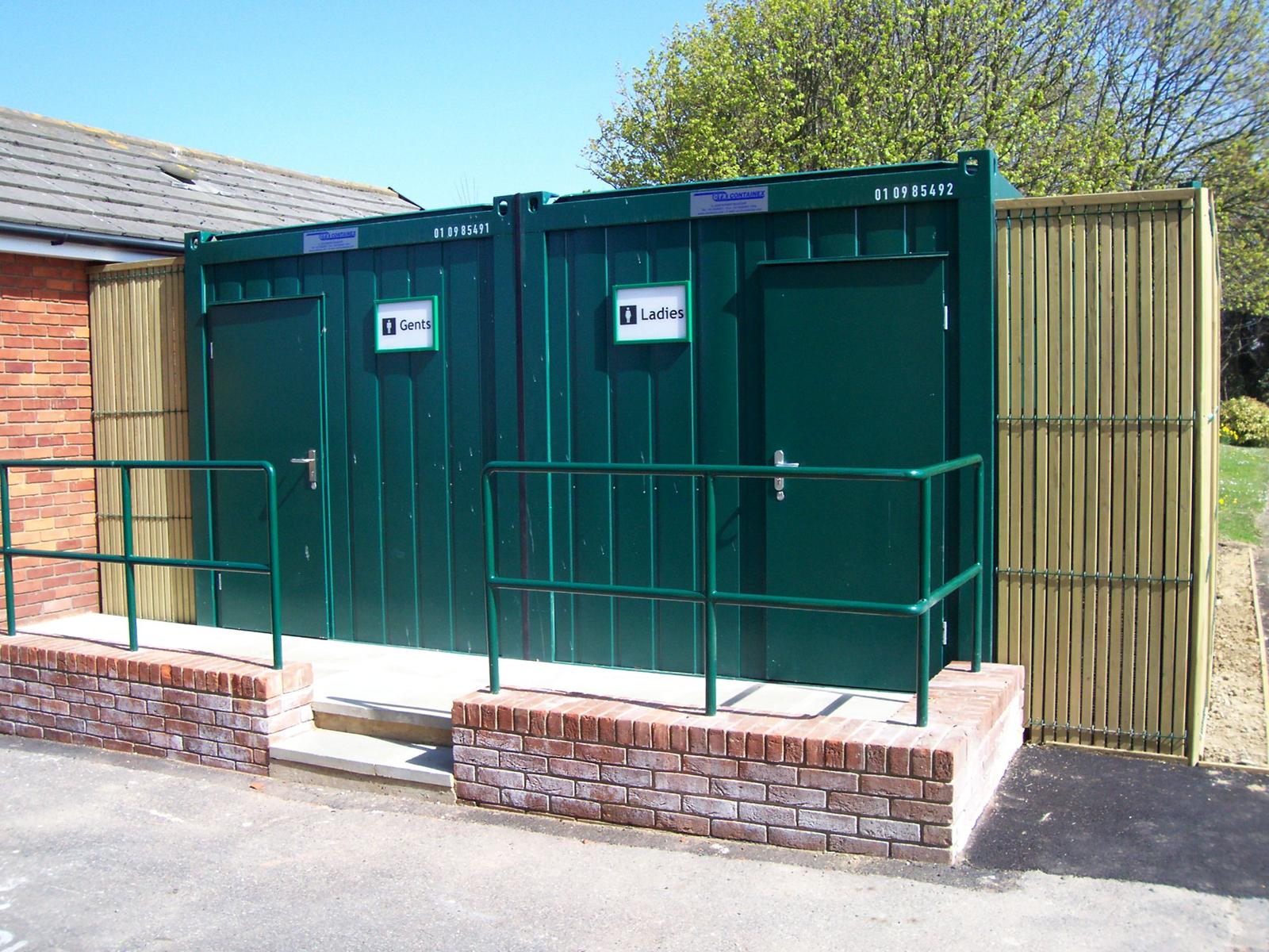 Green modular Gents and Ladies toilet block with brick plinth and handrails