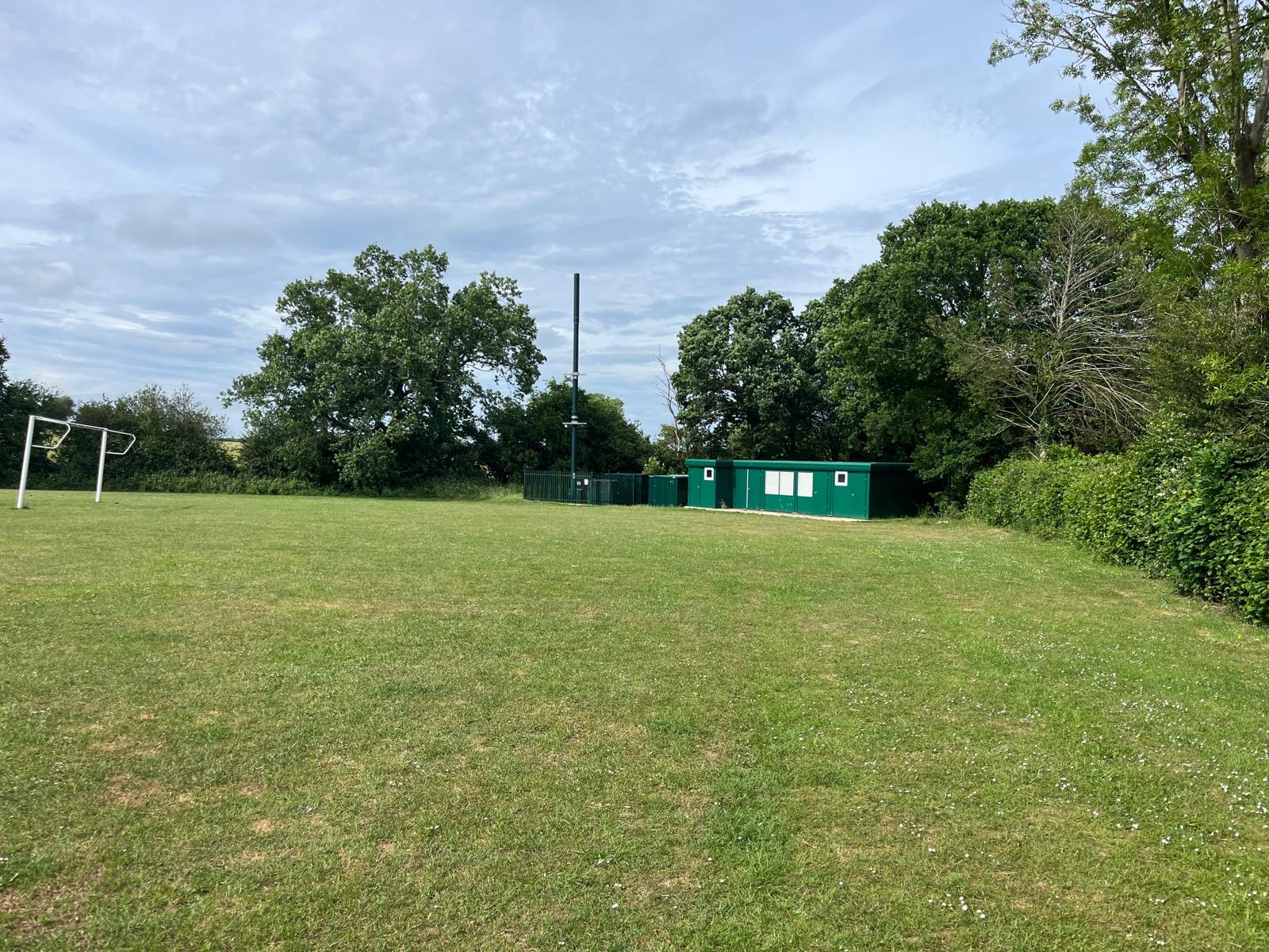 Green modular pavilion building beside a football pitch